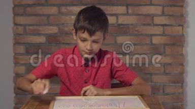 坐在办公桌前的孩子拿着一张挂图，背景红砖墙上刻着百万字。